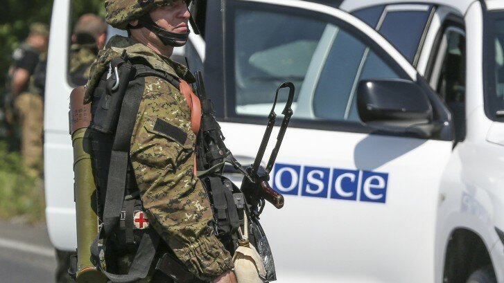 An armed pro-Russian separatist looks next to an OSCE monitoring mission in Ukraine vehicle, on the way to the site where the downed Malaysia Airlines flight MH17 crashed, outside Donetsk